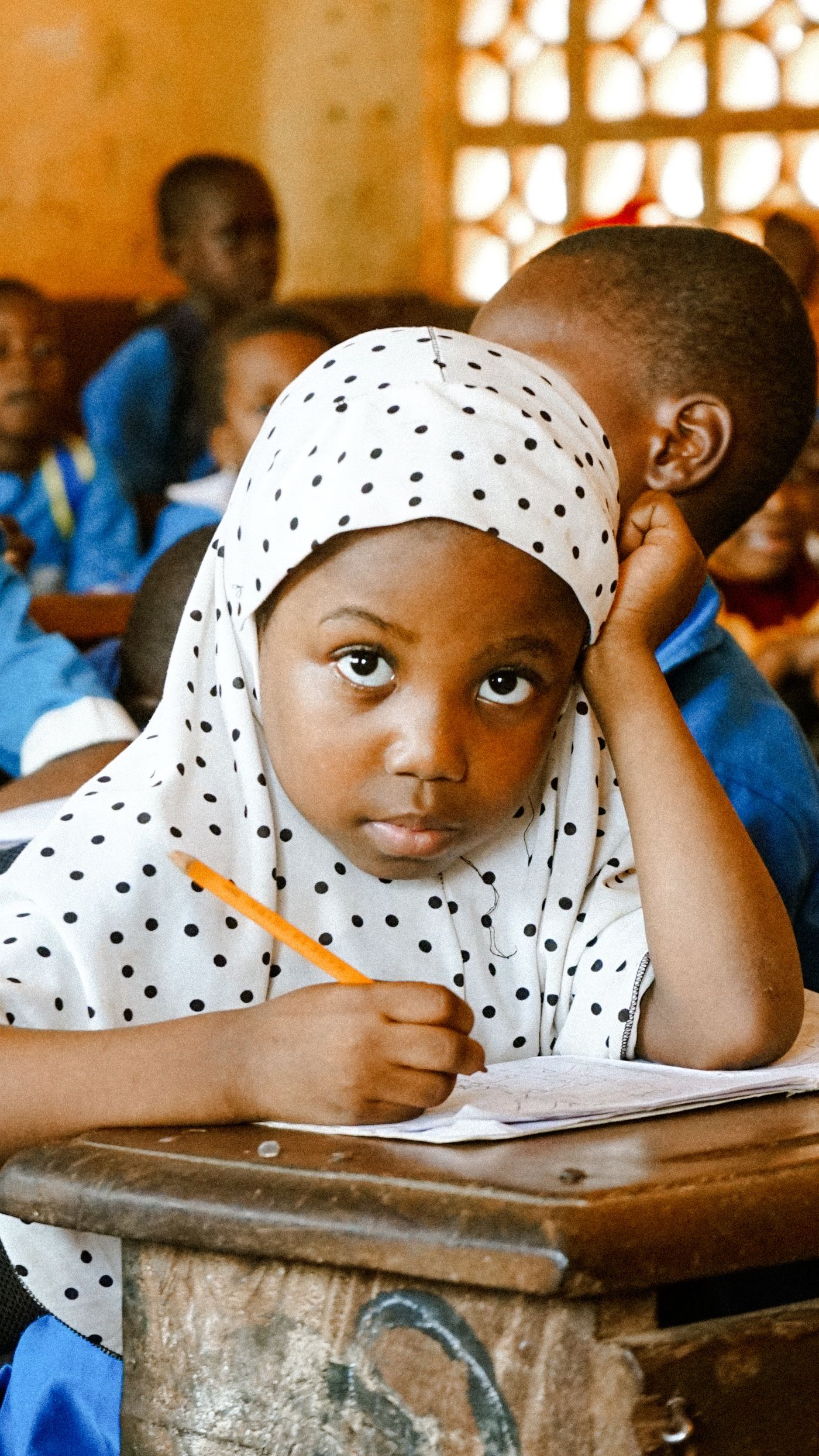 Petite fille concentrée en train d'écrire en classe de maternelle